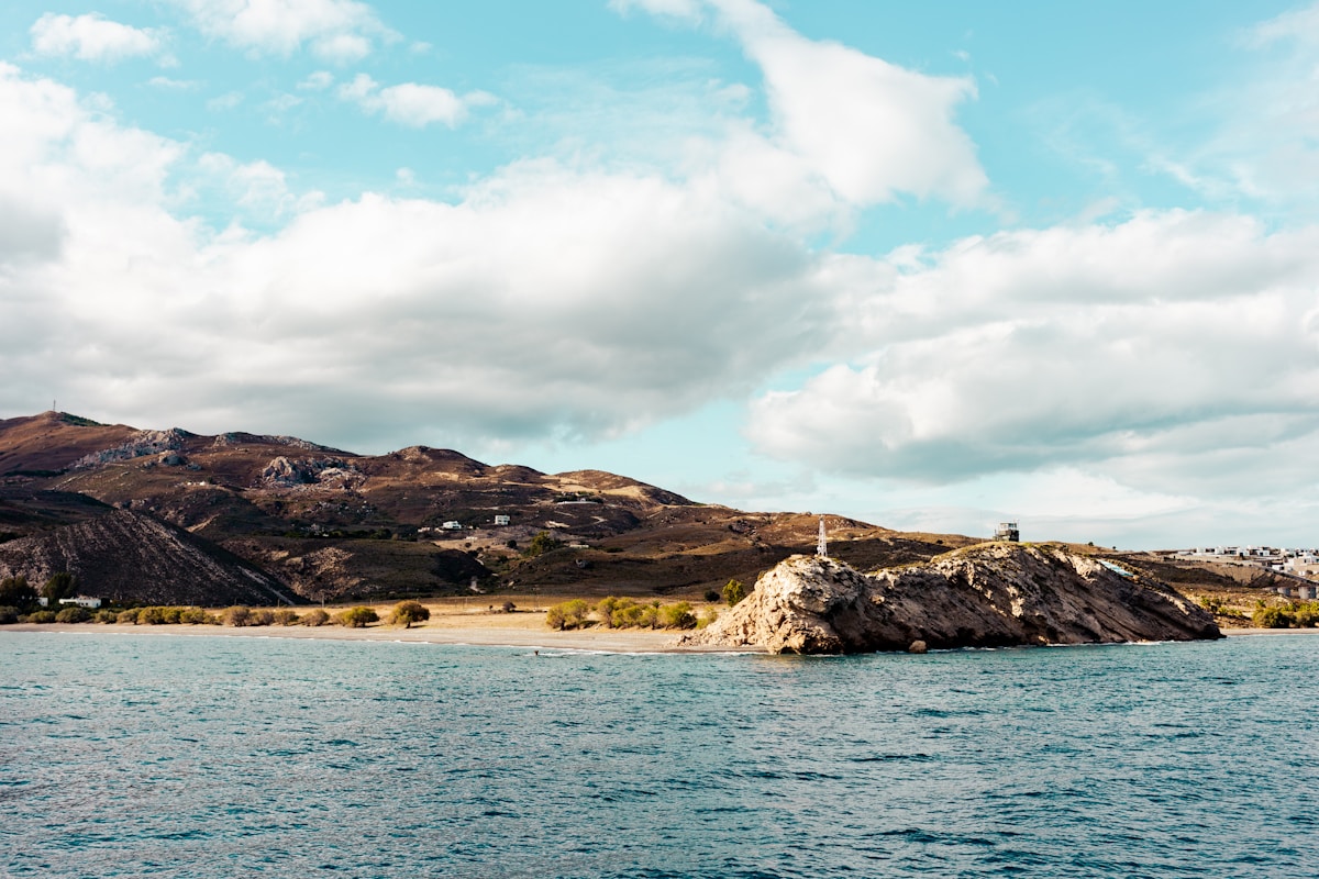 Rocky coastline with small island and sandy beach, Kos island, Greece