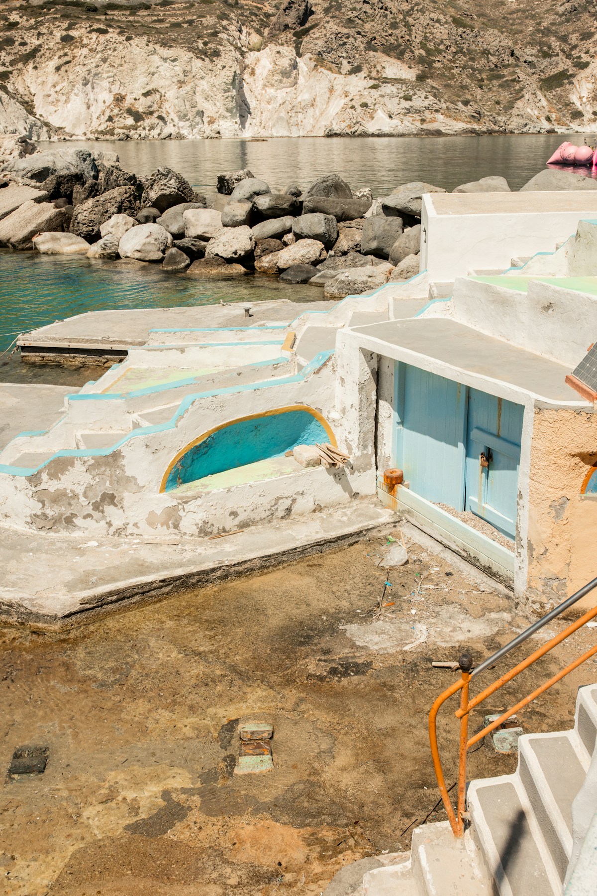 Traditional whitewashed fisherman's boathouse with blue door by the sea, Milos island, Greece