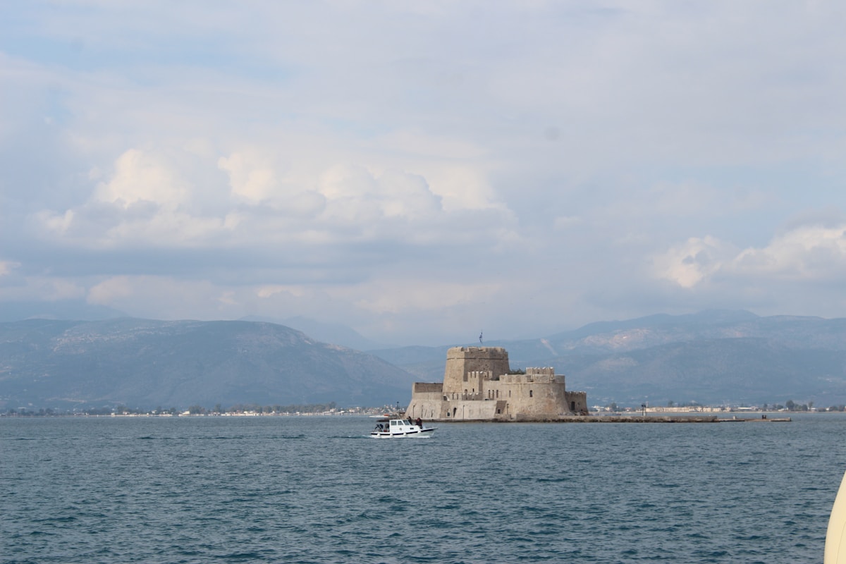 Bourtzi castle sitting on a small island in Nafplio harbour with mountains rising behind it under a cloudy sky