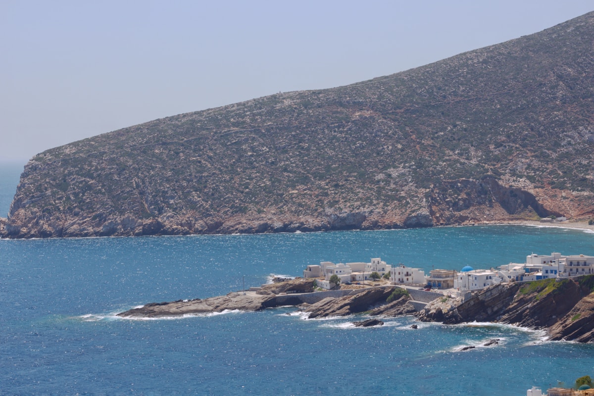 Small village perched on a rocky coastal headland in Naxos, Greece, with turquoise Aegean sea