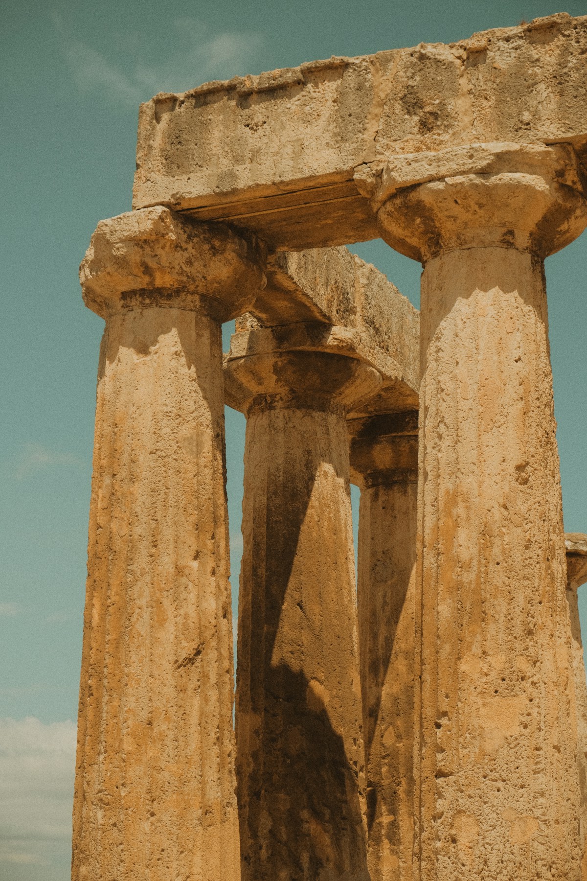 Ancient Doric columns at the archaeological site of Olympia, Greece, under a blue sky