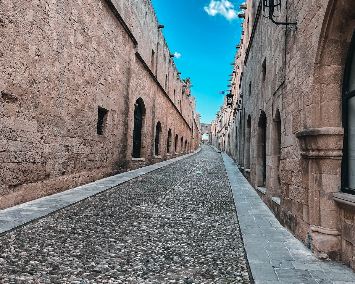 Medieval cobblestone street in Rhodes Old Town, flanked by ancient stone walls
