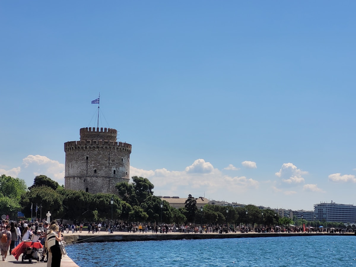 The White Tower of Thessaloniki rising above the waterfront promenade with crowds on a clear summer day