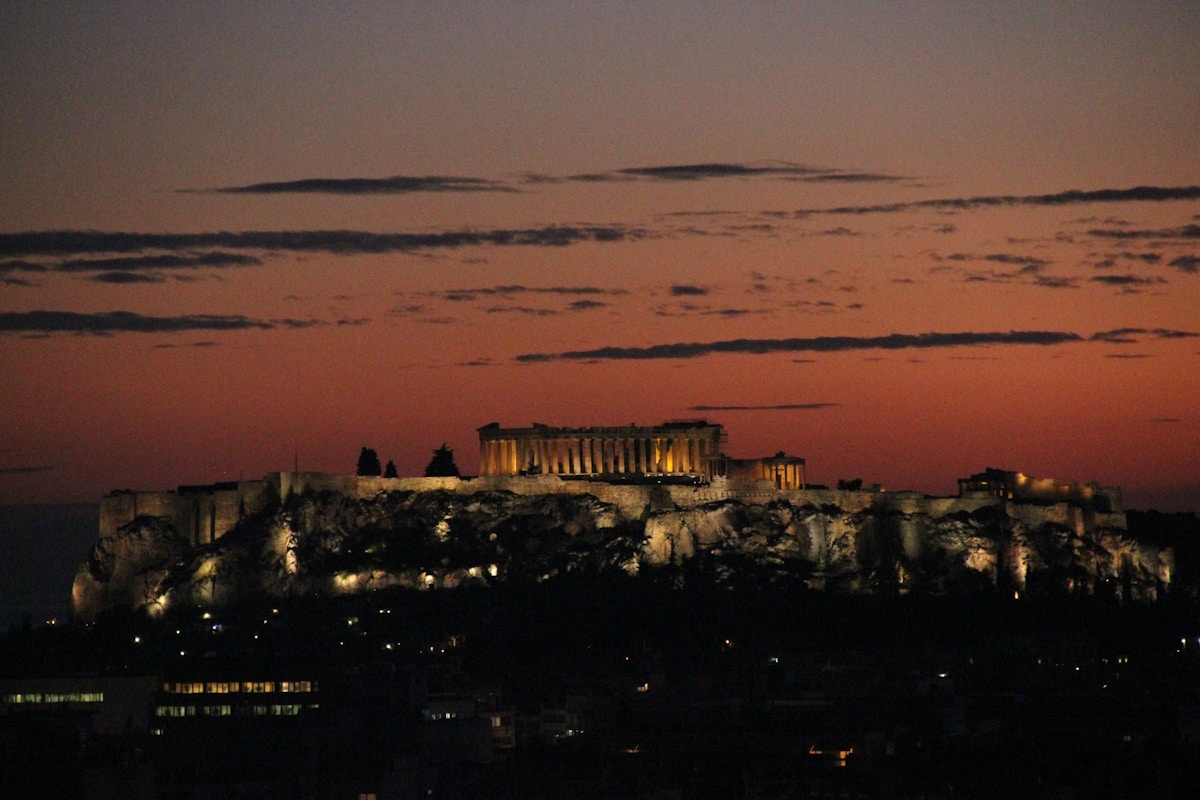 The illuminated Acropolis of Athens glowing against a sunset sky