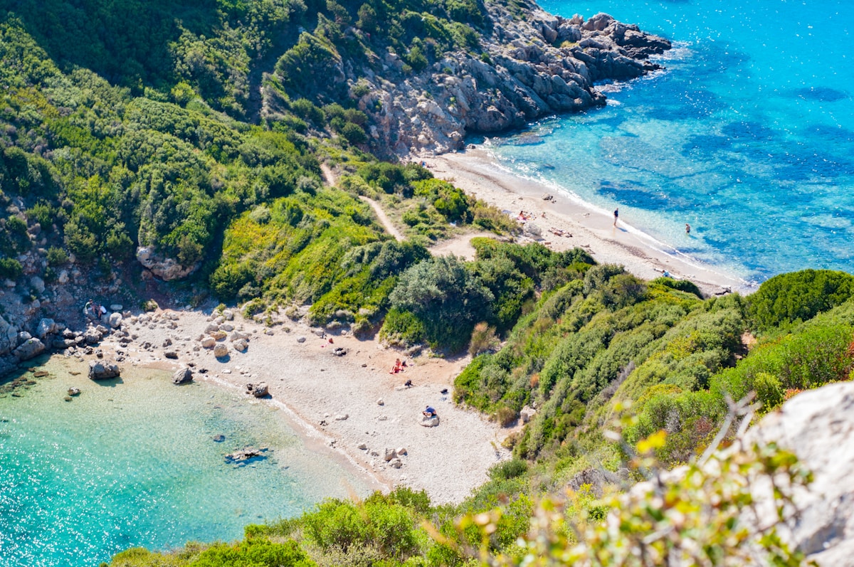 Aerial view of a secluded cove with turquoise water and rocky green cliffs on Corfu, Greece