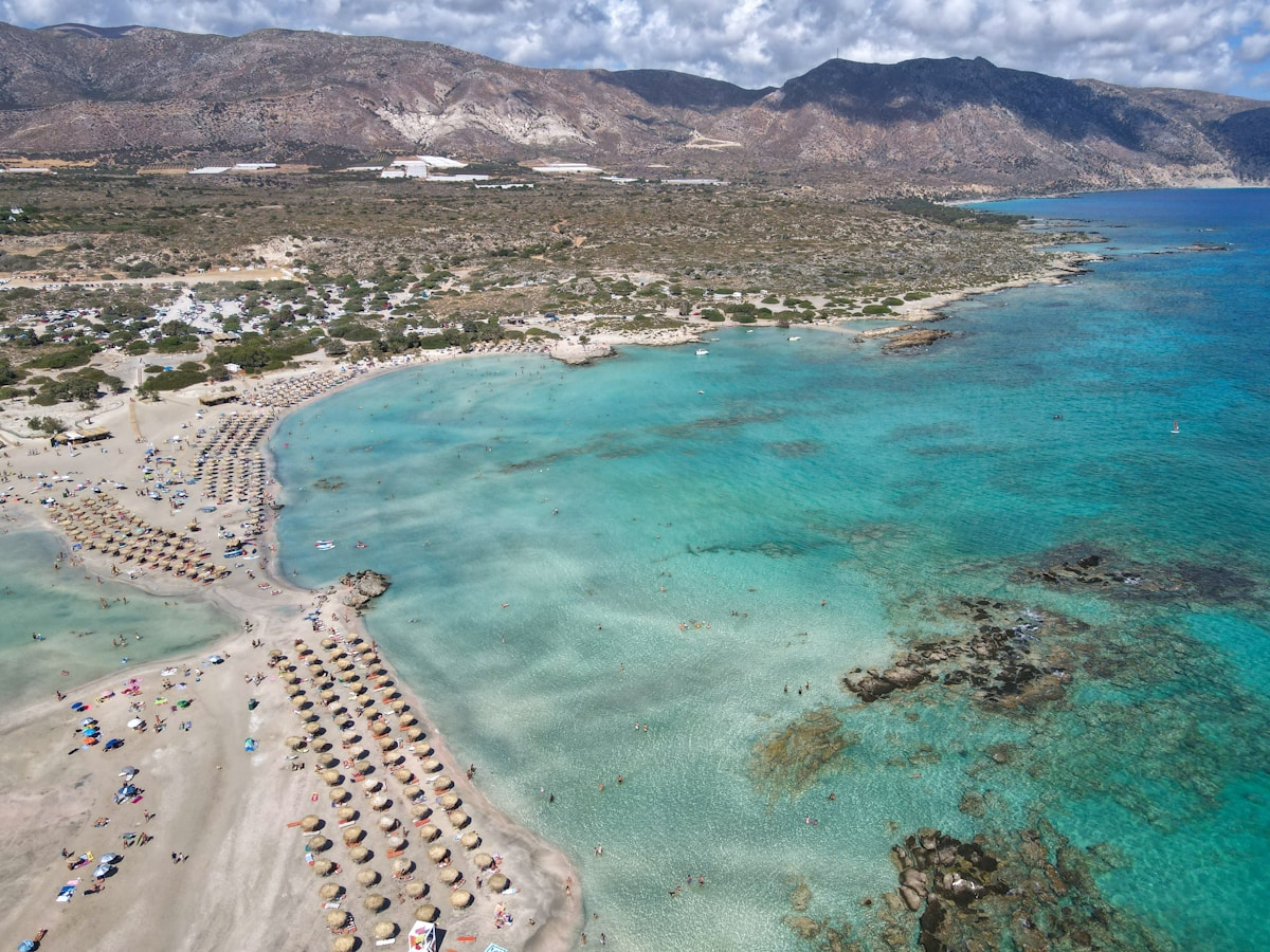 Aerial view of Elafonisi lagoon in western Crete, showing turquoise water and sun umbrellas on the beach