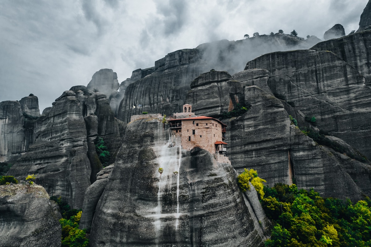 Meteora monastery perched on a sheer sandstone cliff in northern Greece, mist below