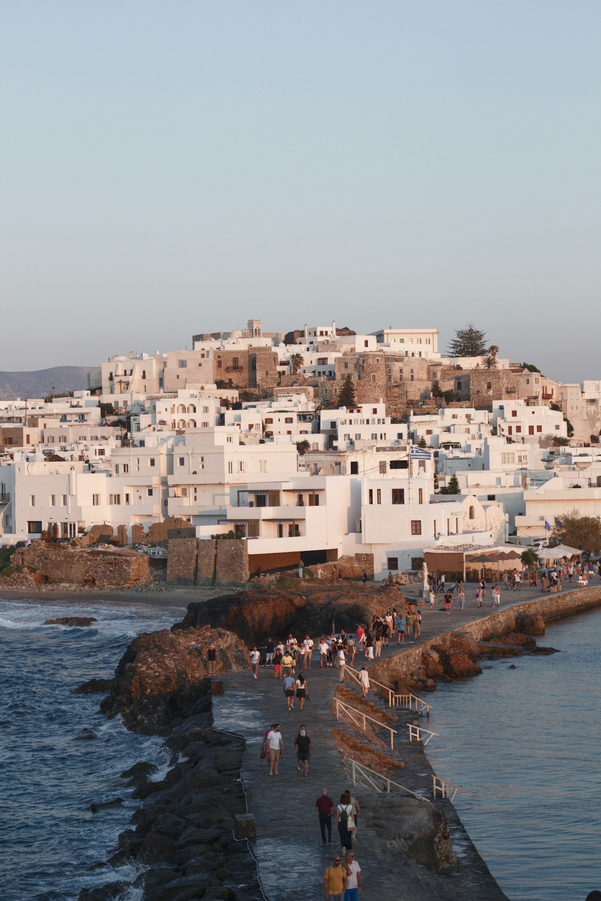 Visitors walking along the causeway towards Naxos town at golden hour