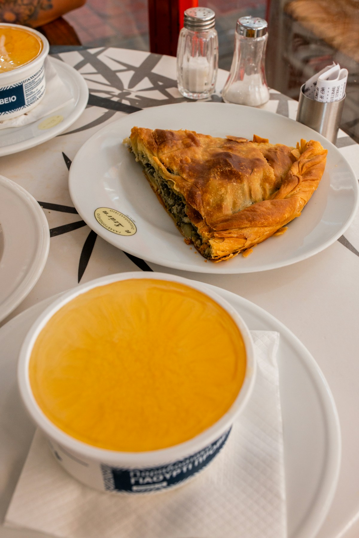 Spanakopita und ein Orangengetränk auf einem gemusterten Tisch, Griechenland