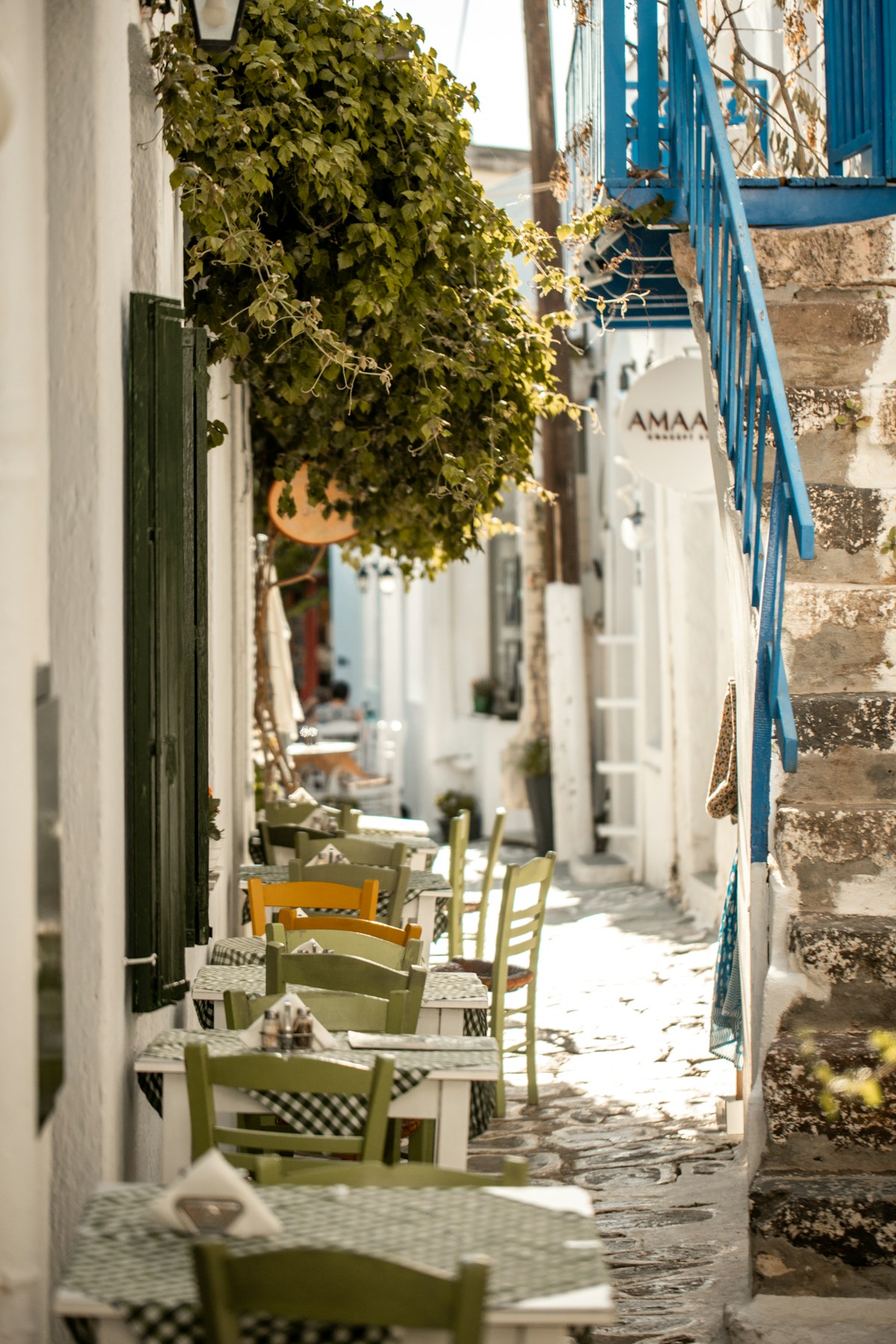 Enge Gasse mit Außensitzplätzen eines Restaurants in Pollonia, Milos, Griechenland